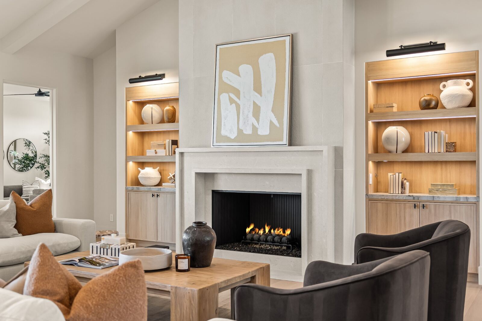 A custom living room with a fireplace and lit built-in shelving