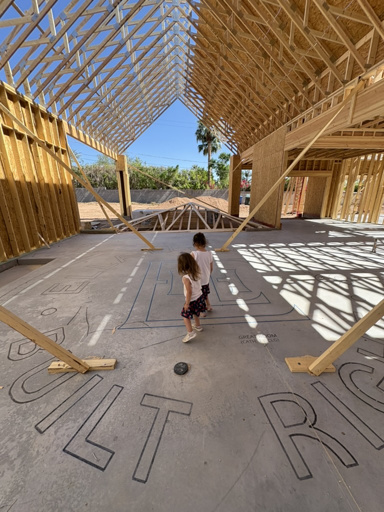 A parent and child walking through the framing of a home under construction