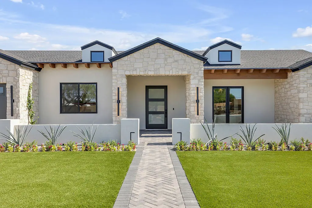 Modern single-story custom home with white walls, stone accents, and a black front door